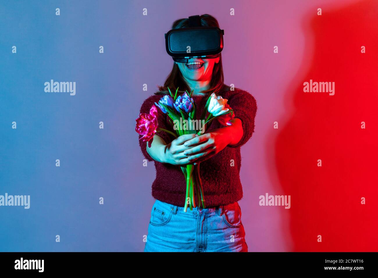 Cheerful girl in VR glasses holding flowers bouquet, giving tulips to