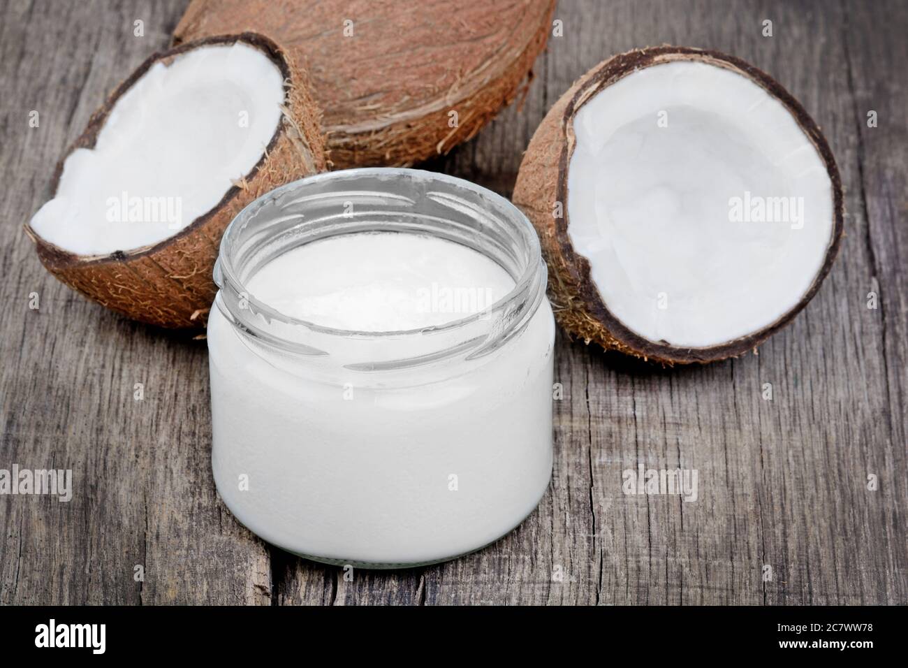 Coconut oil in a jar and coconut fruits on old wood table Stock Photo