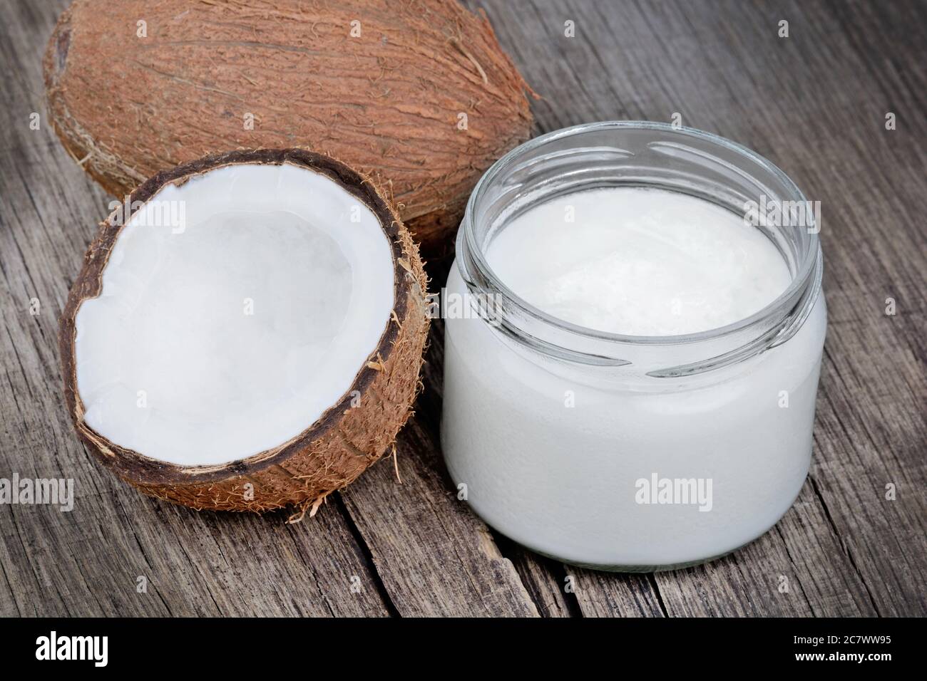 Coconut oil and fresh coconuts on old wooden table Stock Photo