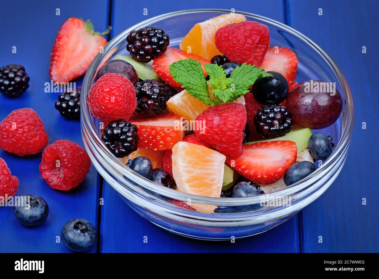 Delicious fruits salad in a bowl on blue wooden table Stock Photo