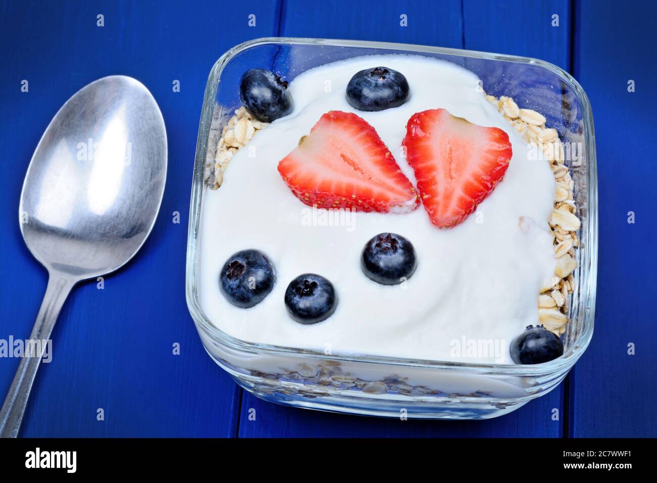 Oat with yogurt and fruits in a bowl on blue wooden table Stock Photo