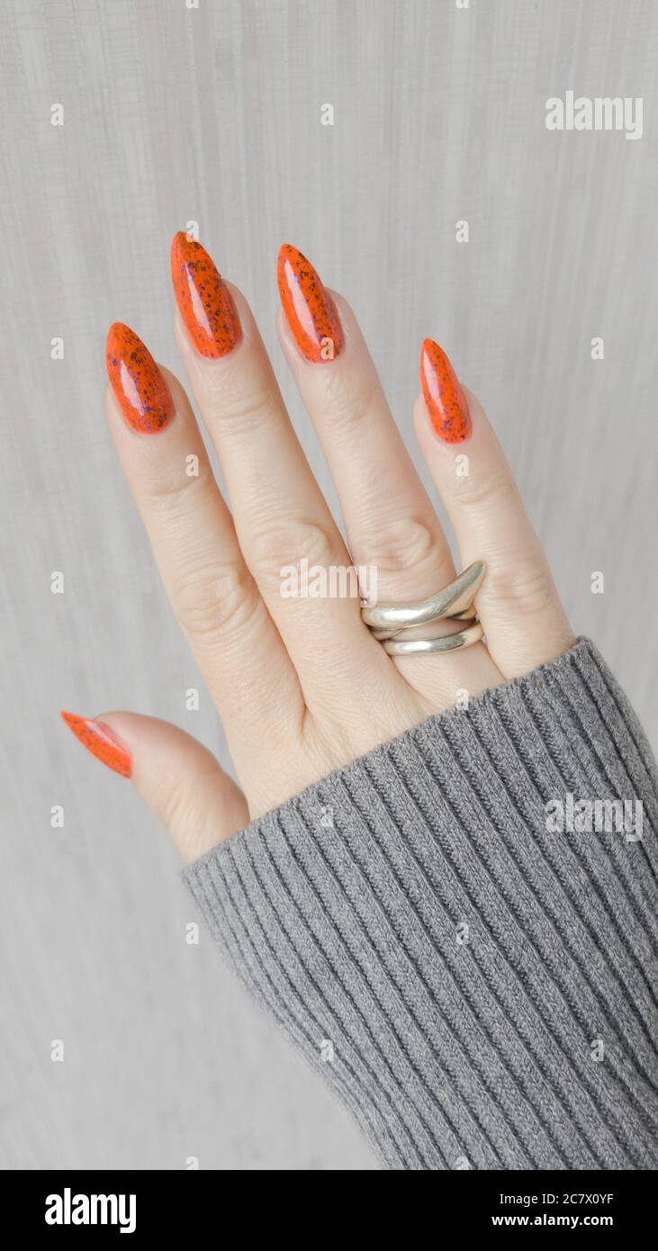 Woman hand with long nails and orange ginger manicure holds a bottle of nail  polish Stock Photo - Alamy