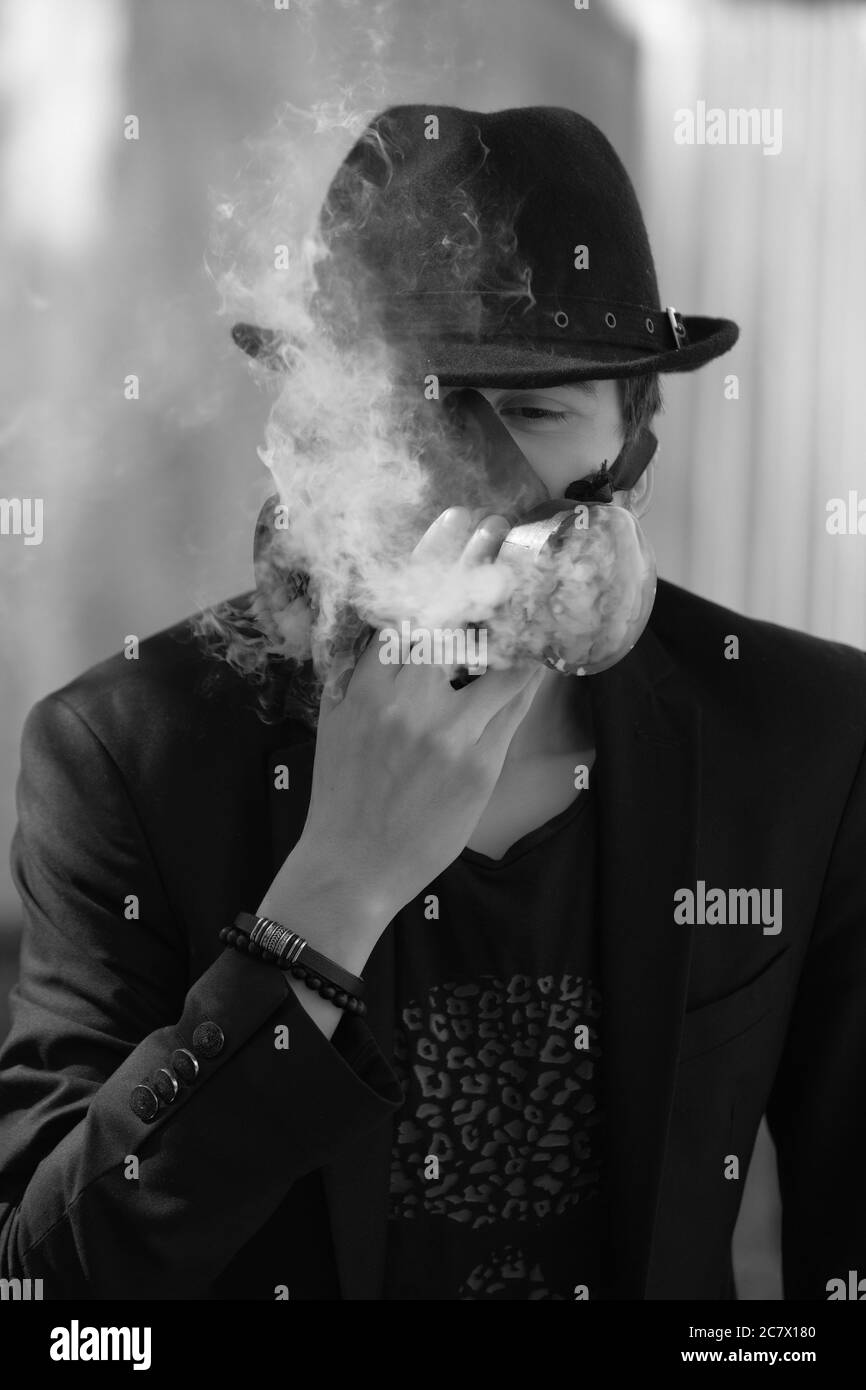 Grayscale portrait of a young male wearing a hat and a respiratory gas mask - anti covid-19 concept Stock Photo