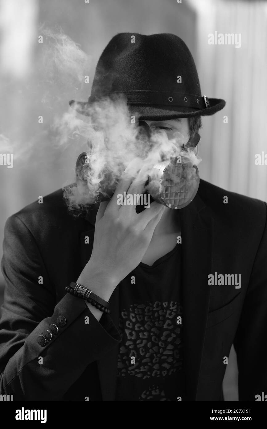 Grayscale portrait of a young male wearing a hat and a respiratory gas mask - anti covid-19 concept Stock Photo