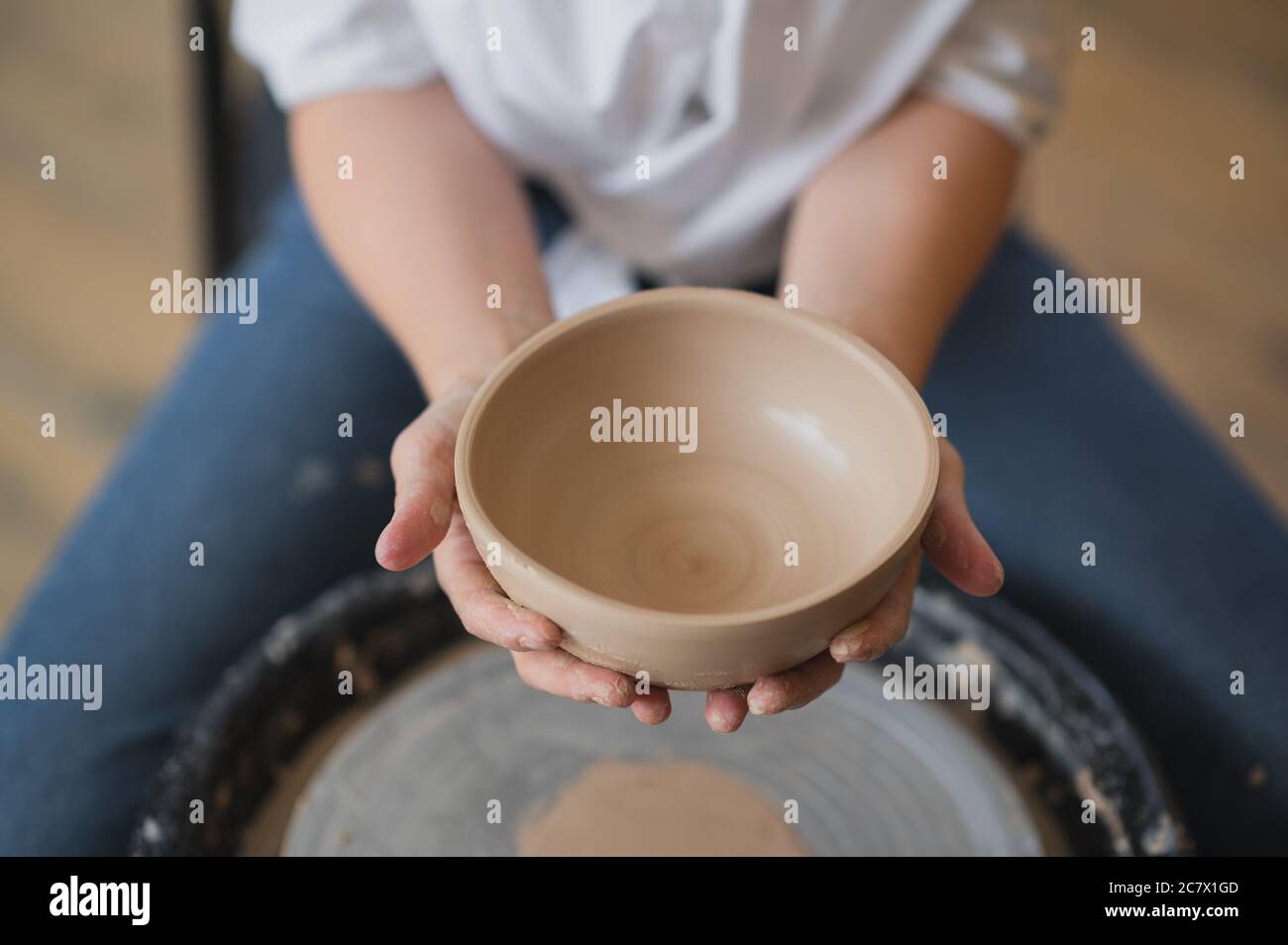 Cuts of product with wire. Craftsman hands making pottery bowl. Woman working on potter wheel. Family business shop sculpts pot from clay. Stock Photo