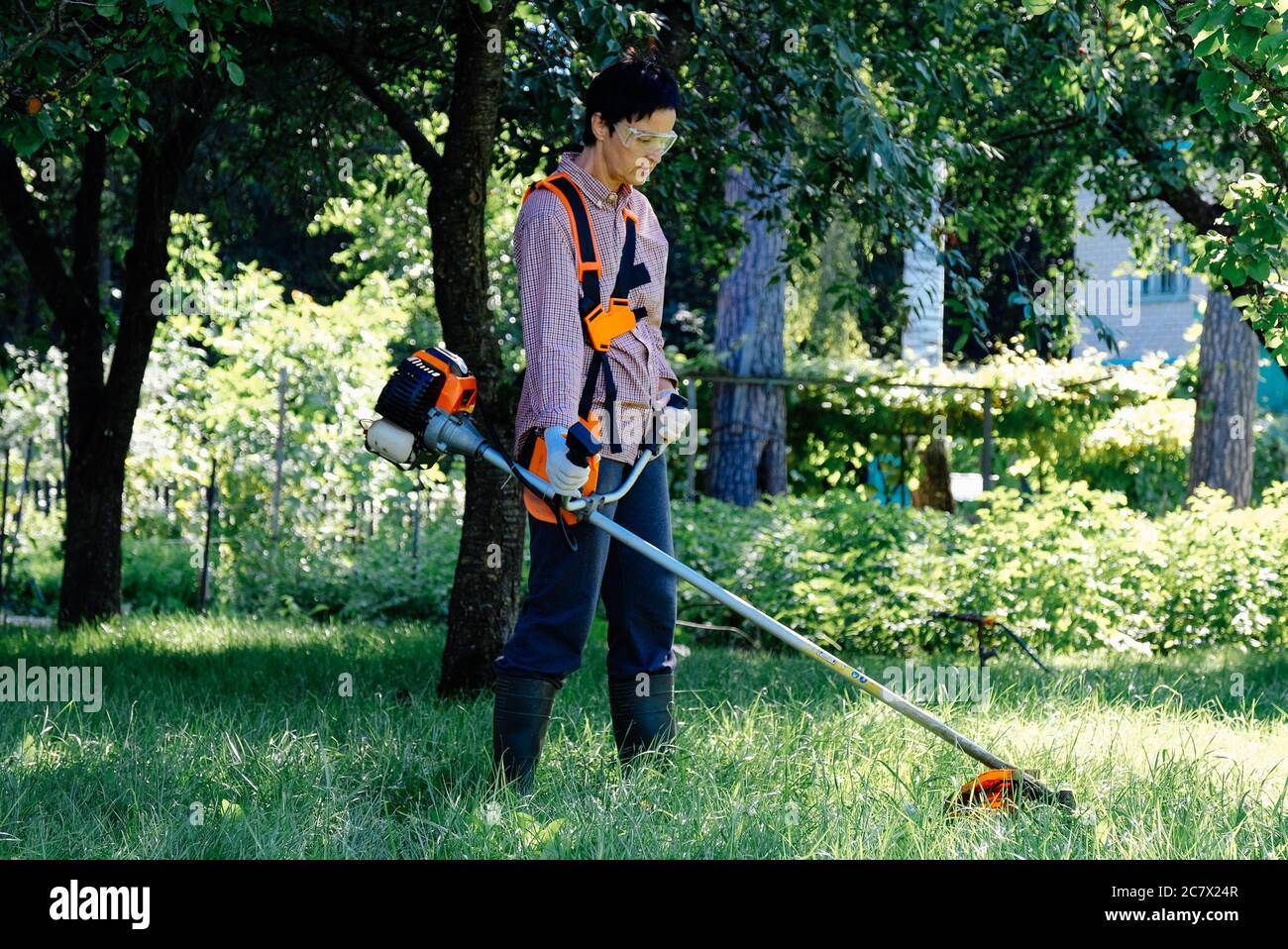 Woman mowing the grass in garden. Lawn care concept Stock Photo