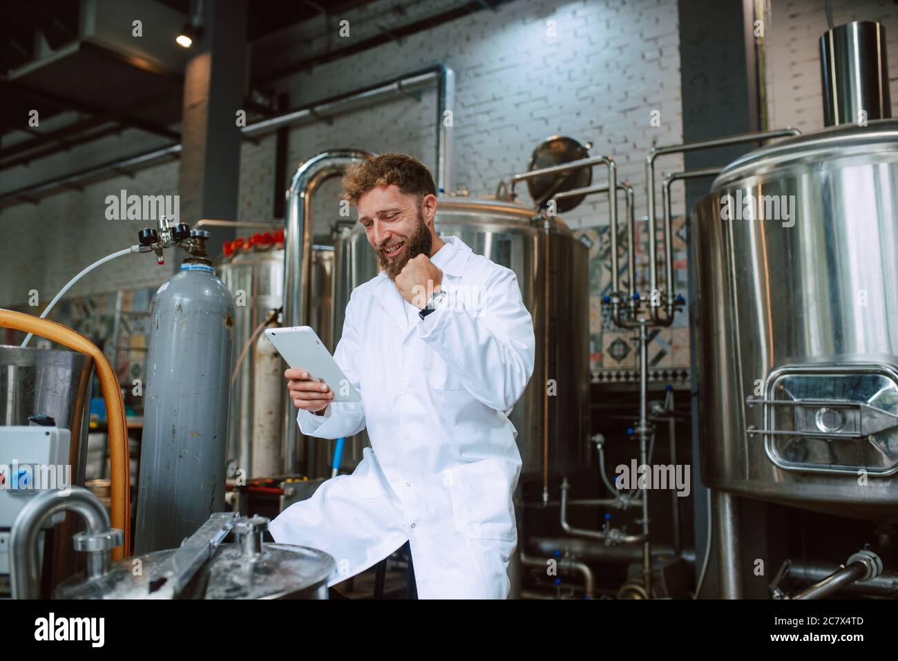 Professional caucasian technologist expert in white uniform in  food factory  - production plant checking productivity and using tablet Stock Photo