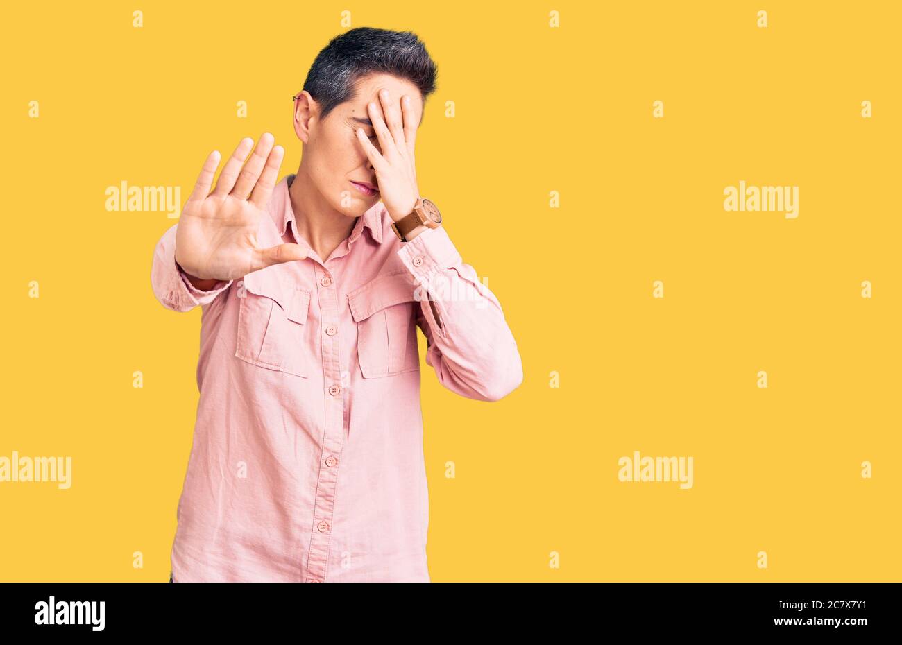 Young woman with short hair wearing casual clothes covering eyes with hands and doing stop gesture with sad and fear expression. embarrassed and negat Stock Photo