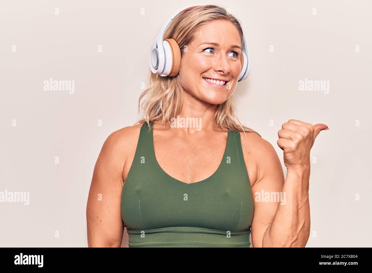 Middle age caucasian blonde woman listening to music using headphones ...