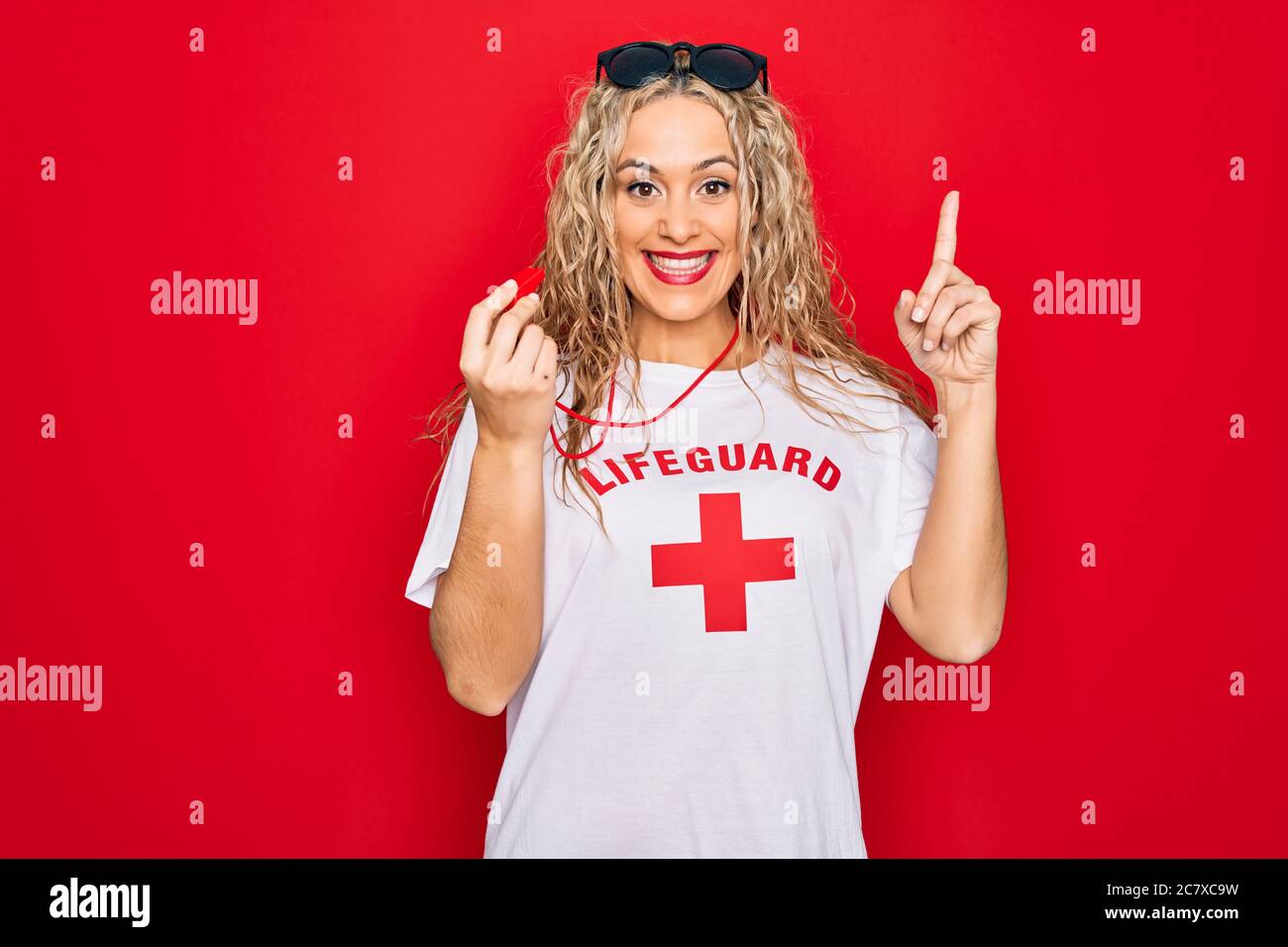 Young beautiful blonde lifeguard woman wearing t-shirt with red cross ...