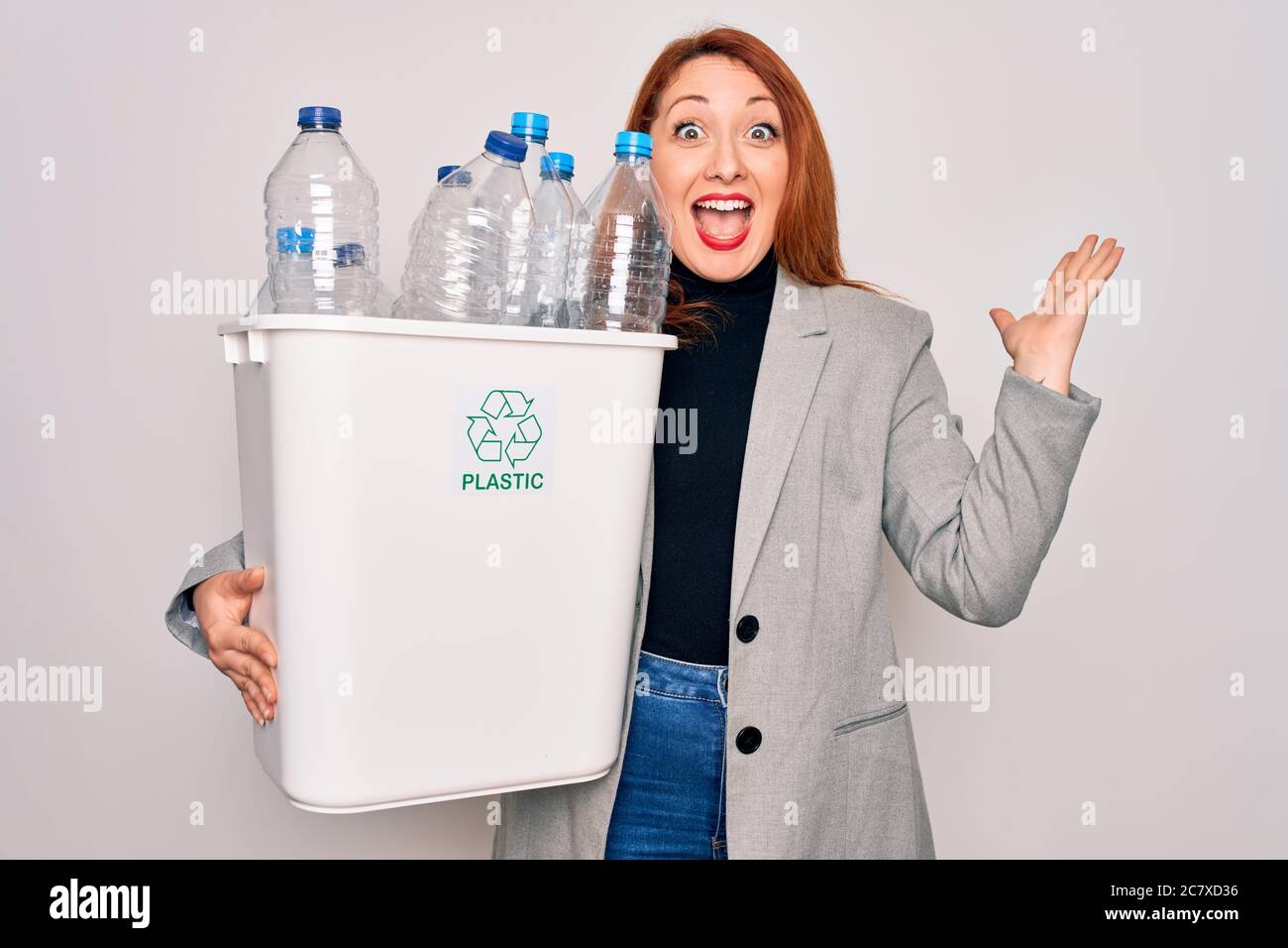 Young beautiful redhead woman recycling holding trash can with plastic