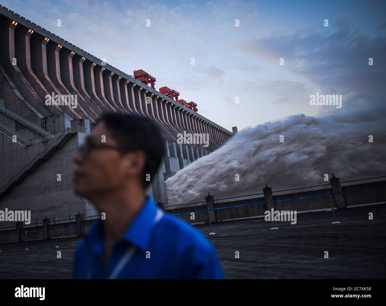 Yichang. 20th July, 2020. A staff member inspects the Three Gorges Dam as floodwater is discharged from the hydraulic structure in central China's Hubei Province. The second flood of China's Yangtze River this year has smoothly passed the Three Gorges Dam on Sunday as the inflow into the reservoir has decreased. The Three Gorges reservoir saw an inflow of 46,000 cubic meters per second at 8 p.m. Sunday, compared with a peak of 61,000 cubic meters per second, which appeared at 8 a.m. Saturday and lasted for 18 hours. Credit: Xiao Yijiu/Xinhua/Alamy Live News Stock Photo