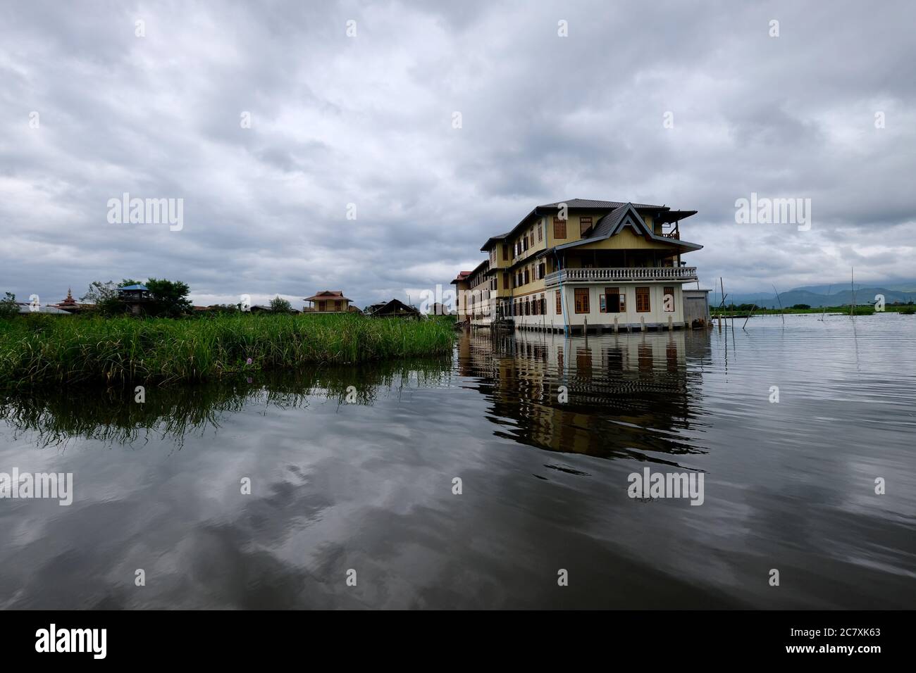 traditional house and floating green plants on Inle lake Myanmar. Cloudy sky and beautiful reflection in water Stock Photo