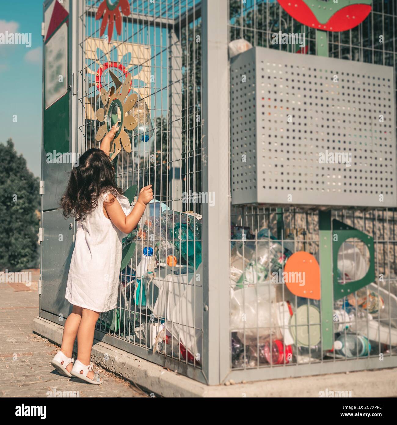 Little Girl Recycling Empty Plastic Water Bottles in Metal Recycling
