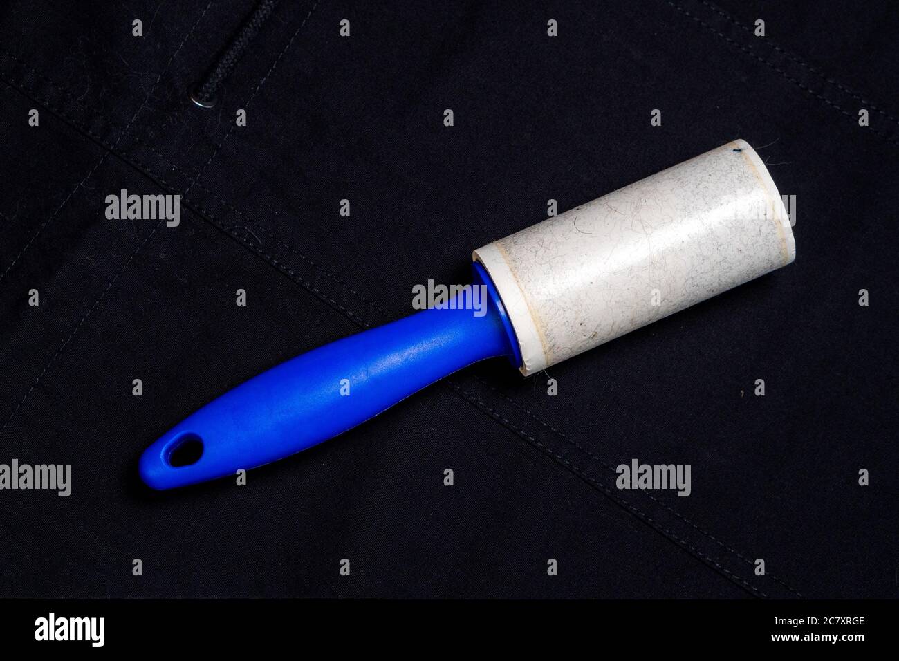 Adhesive roller for cleaning cloth on a black cloth. Top view Stock Photo