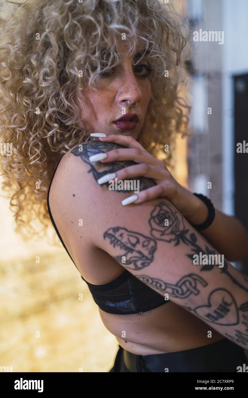 Shallow focus of a beautiful blonde woman with curly hair and tattoos Stock Photo - Alamy