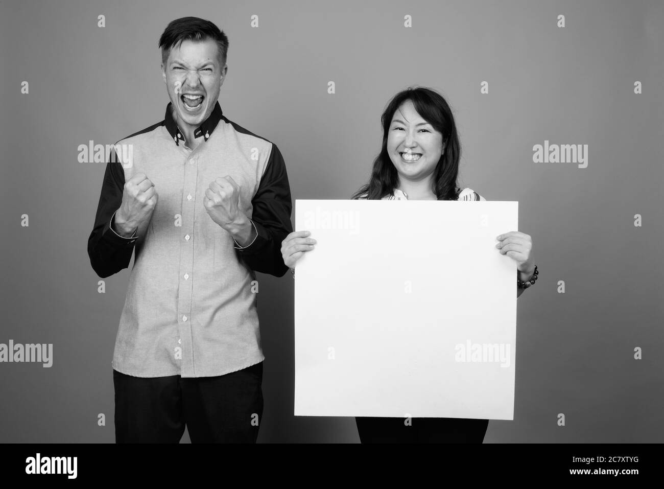 Portrait of young handsome businessman and mature Asian businesswoman together with white board Stock Photo