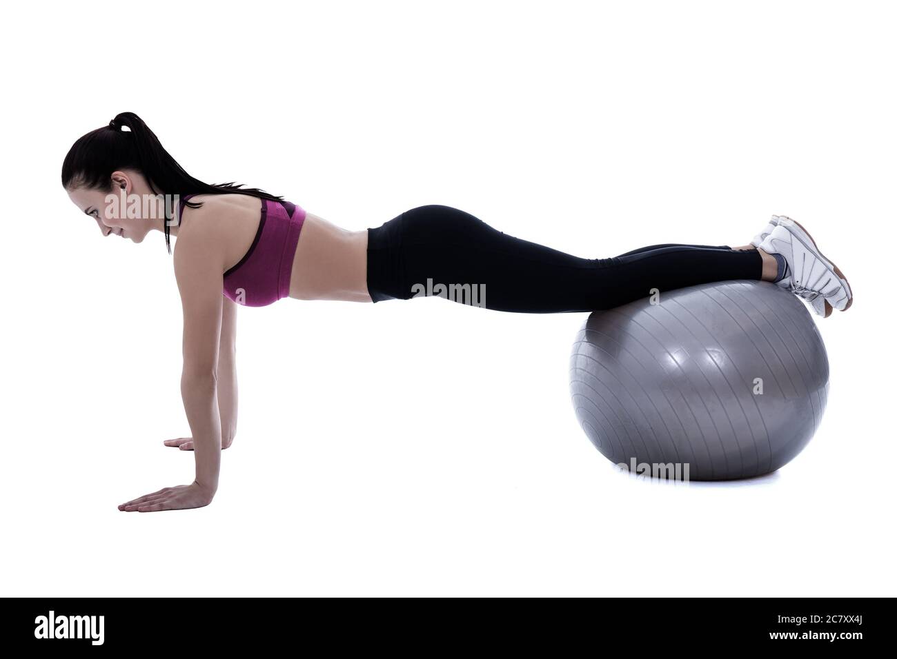 silhouette of slim woman in sports wear doing push up exercises on fitness ball isolated on white background Stock Photo