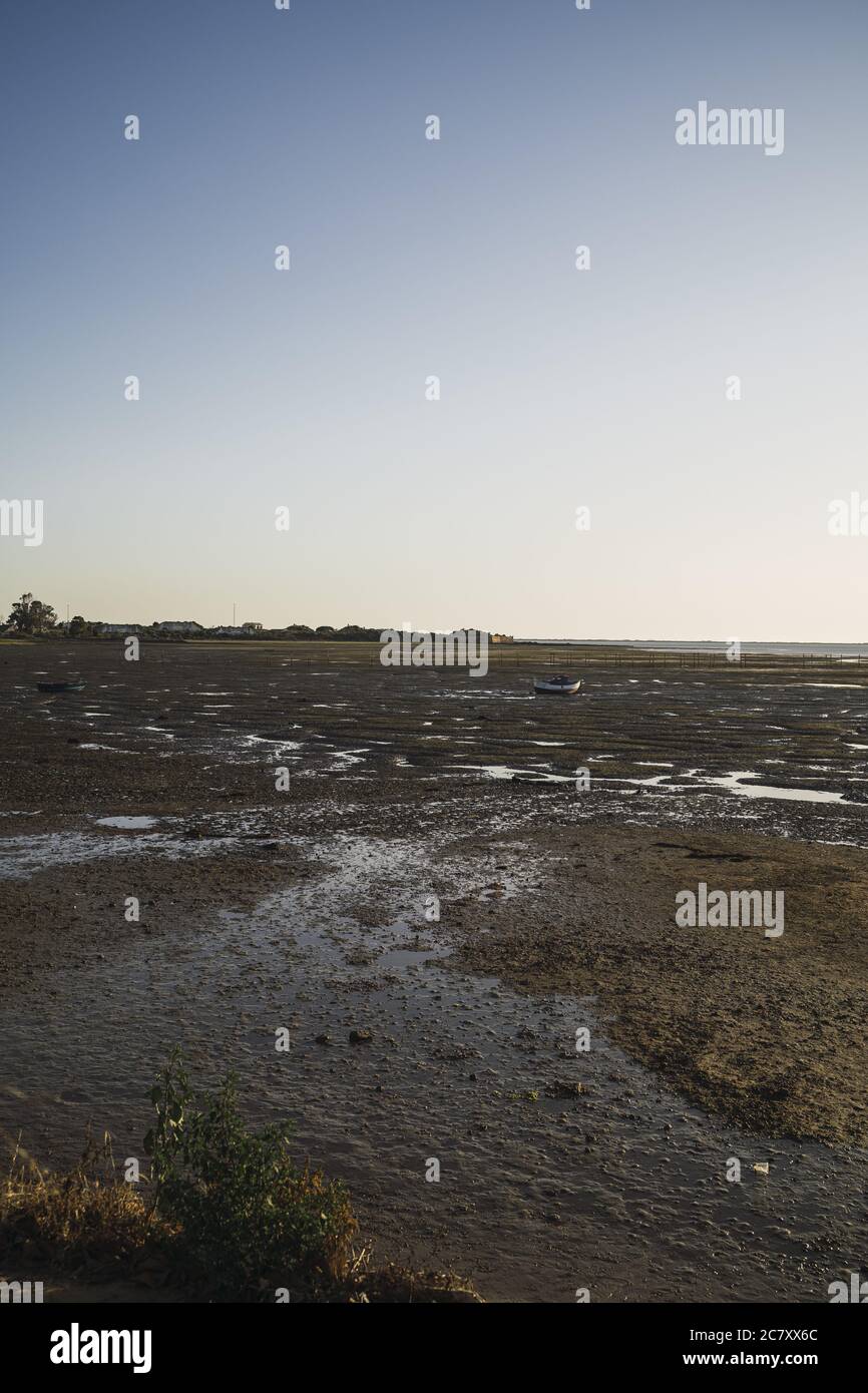 Vertical shot of a dried out lake with boats stuck in the dry land and small ponds of water Stock Photo