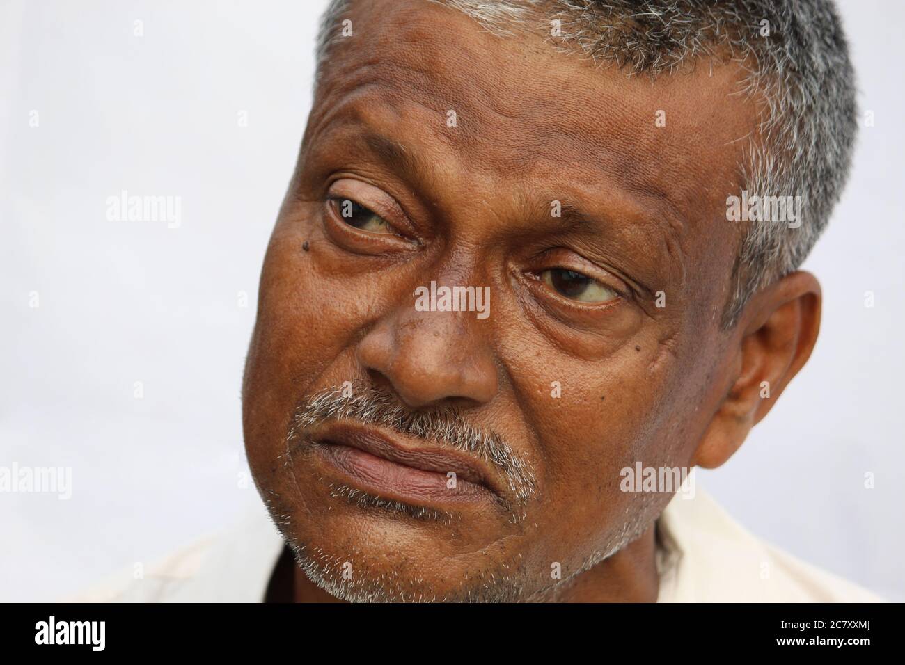 Sad or thoughtful senior Indian man face portrait on white background. Old man looking side way. Stock Photo