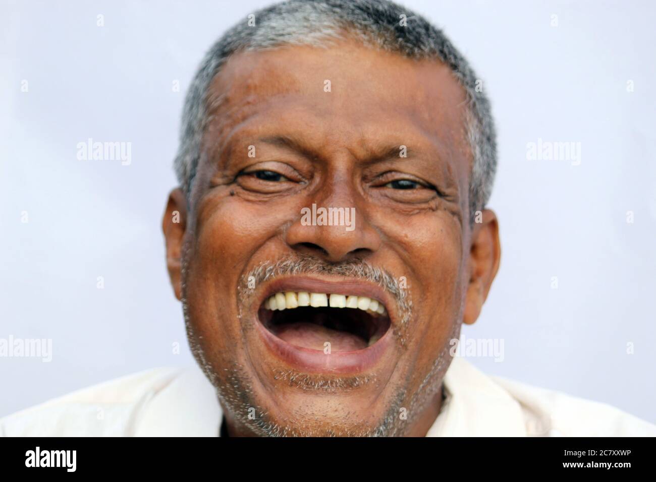 Loud laughing open mouth of a Indian senior man on white background. Stock Photo