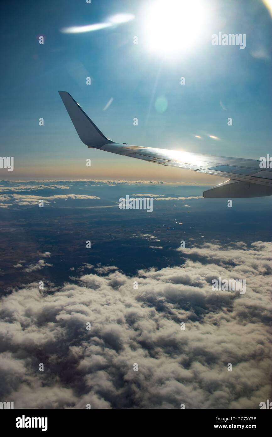Airplane wing high above the clouds in the bright blue sky Stock Photo ...
