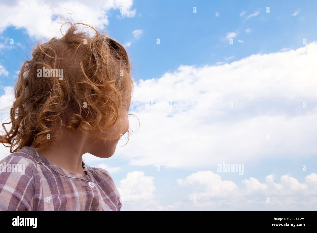 little girl looking at the blue sky with clouds, air travel concept ...