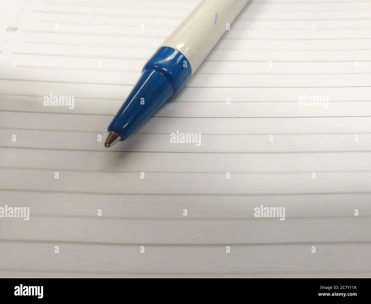 White and blue pan put on the sheet of paper with horizontal lines ...