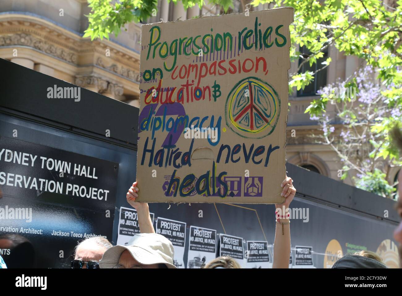 A protester holds a sign saying, ‘progression relies on compassion, education & diplomacy. Hatred never heals’ at the Sydney rally against war in Iraq Stock Photo