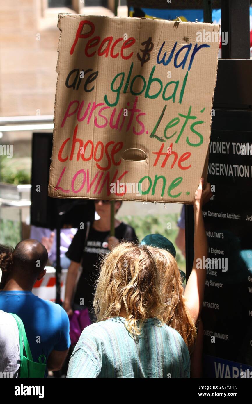 A protester holds a sign saying, ‘Peace & war are global pursuits. Let’s choose the loving one.’ Stock Photo