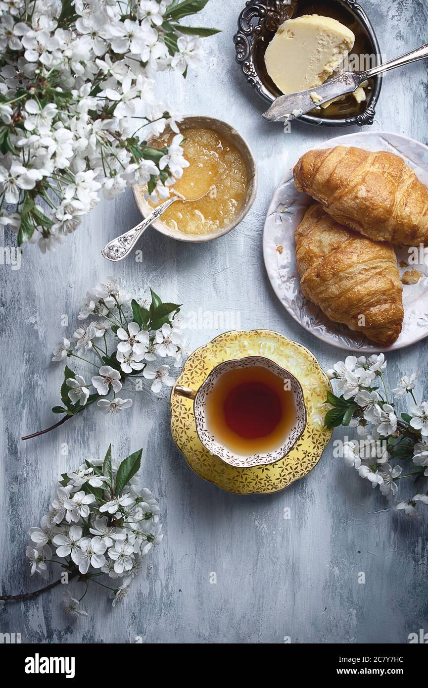 food flatlay on table with morning tea, flowers, honey, butter and croissants, copy space Stock Photo