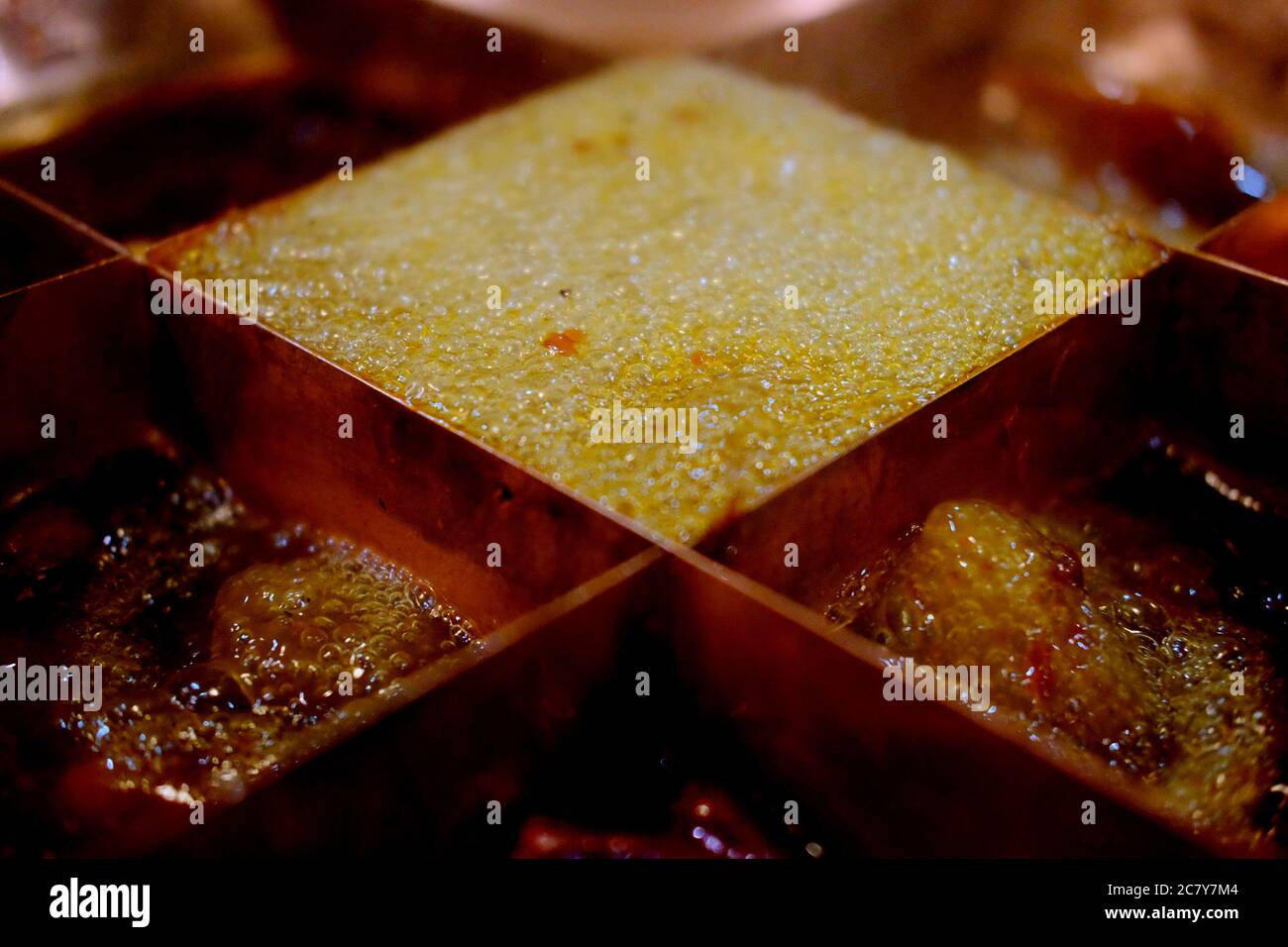 close up oil foam of boiling spicy hot pot. popular Chinese Szechwan chengdu cuisine. Blur background Stock Photo