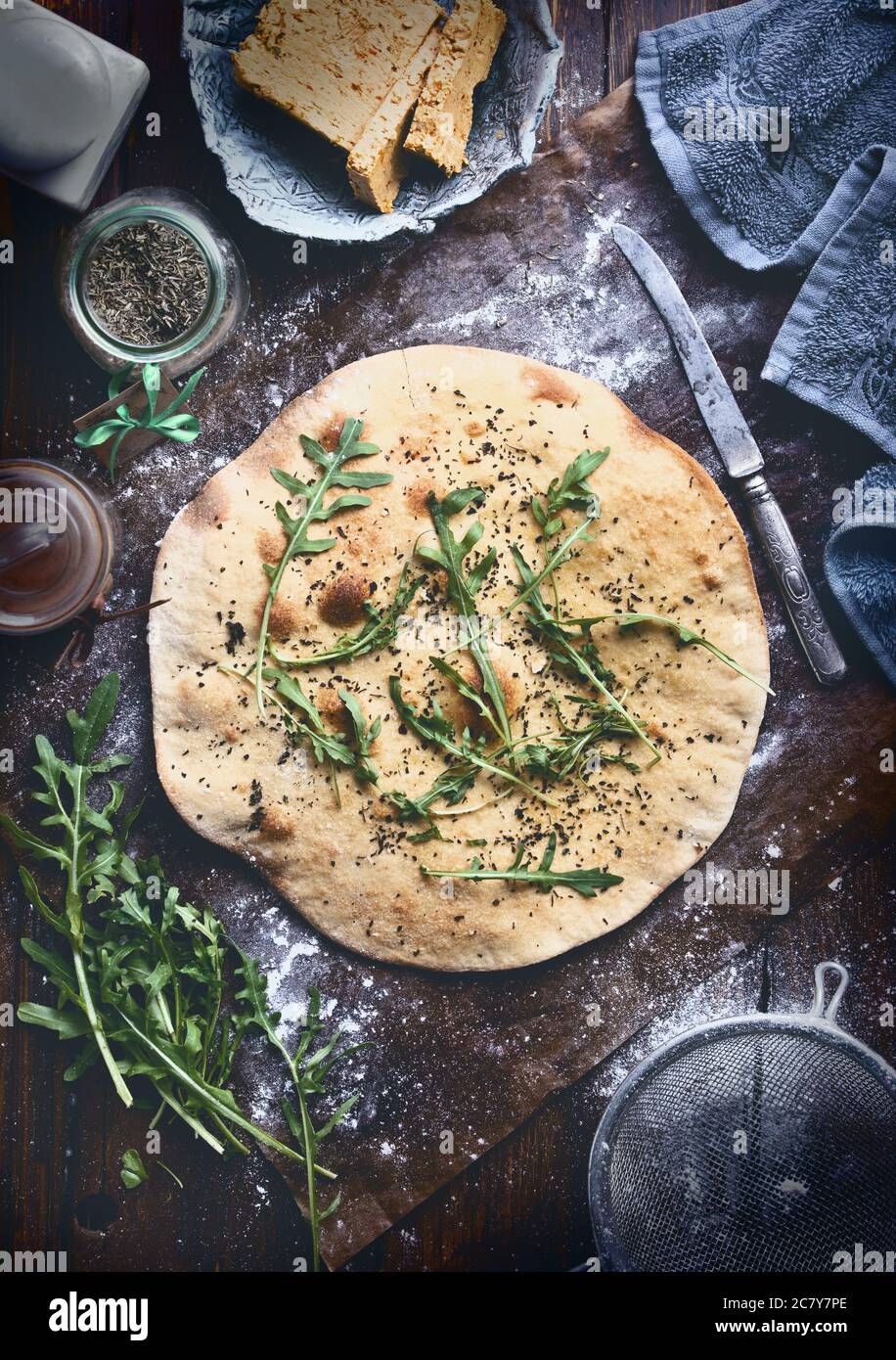 italian food preparation background with focaccia, butter, ruccola and dishwear on old rustic wooden table Stock Photo