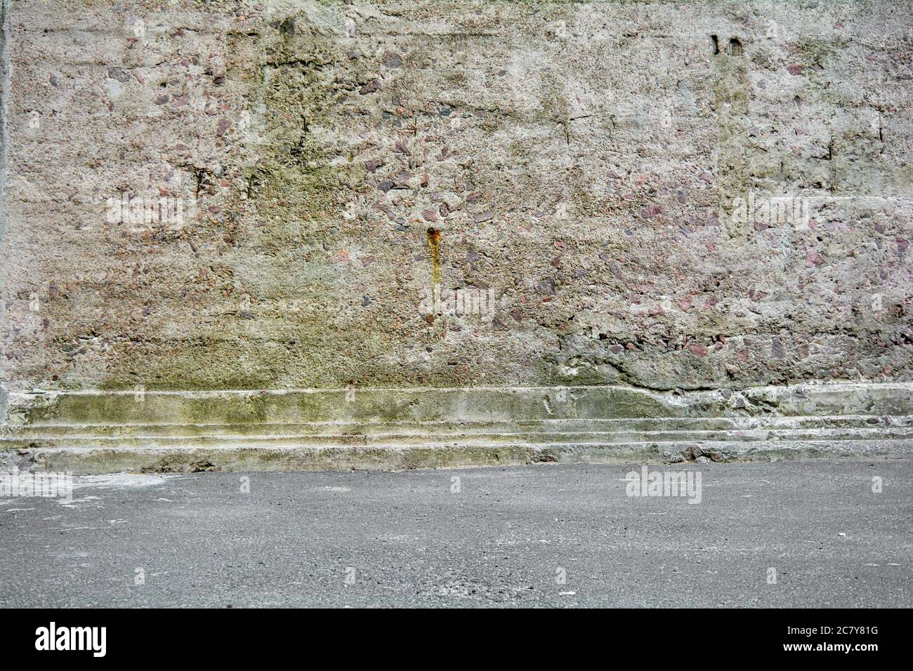 Grunge city background with mossy old stone wall with concrete molding and asphalt Stock Photo