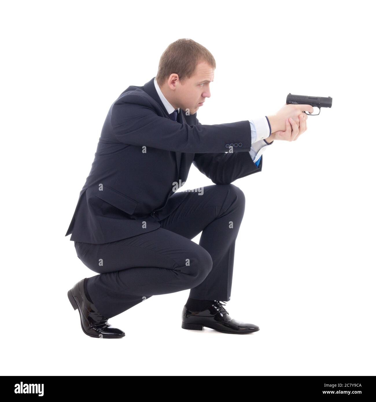 special agent man in business suit sitting and shooting with gun isolated on white background Stock Photo