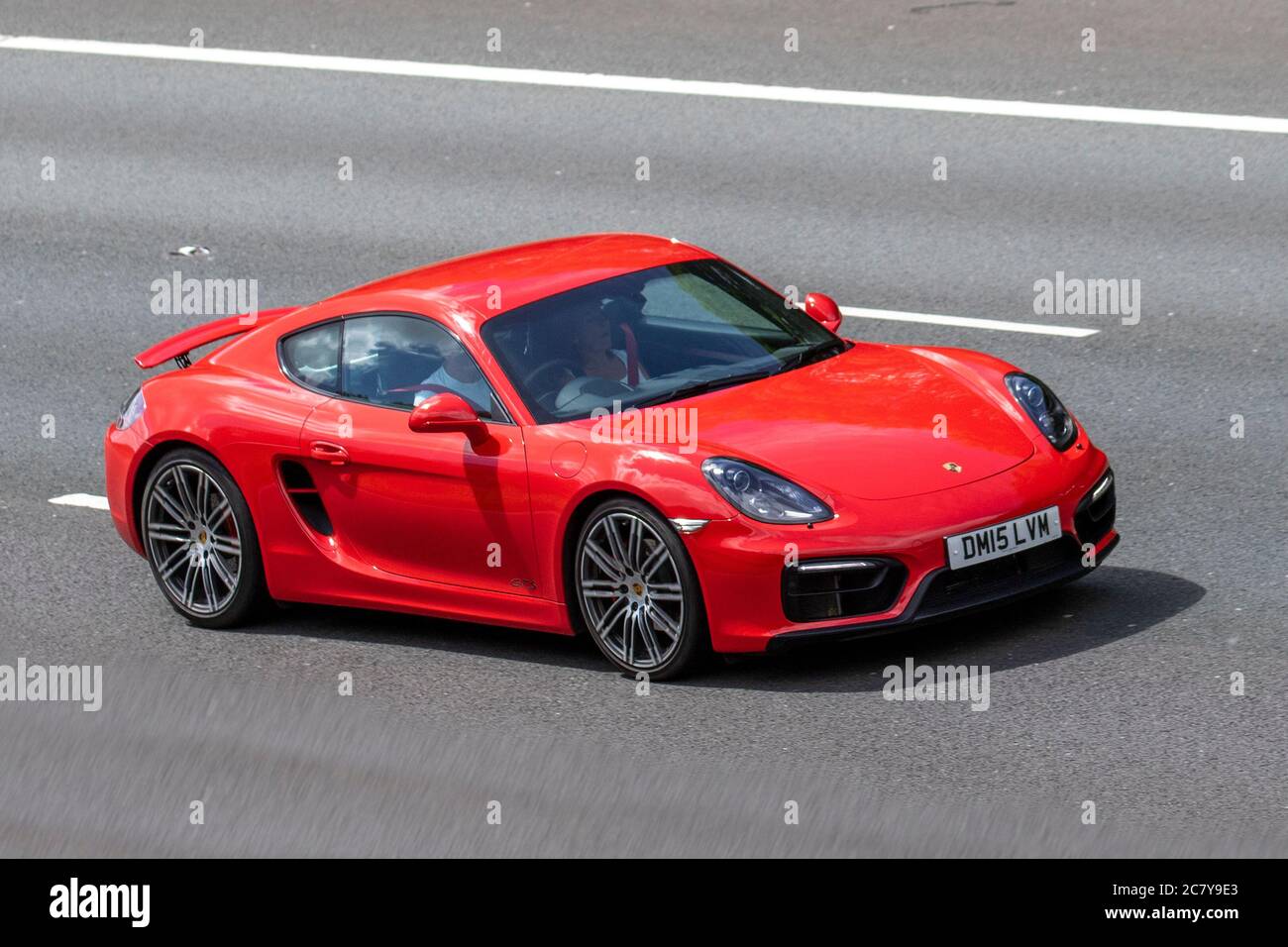 2015 red Porsche Cayman GTS S-A with spoiler up ; Vehicular traffic moving vehicles, cars driving vehicles on UK roads, motors, motoring on the M6 motorway highway network. Stock Photo