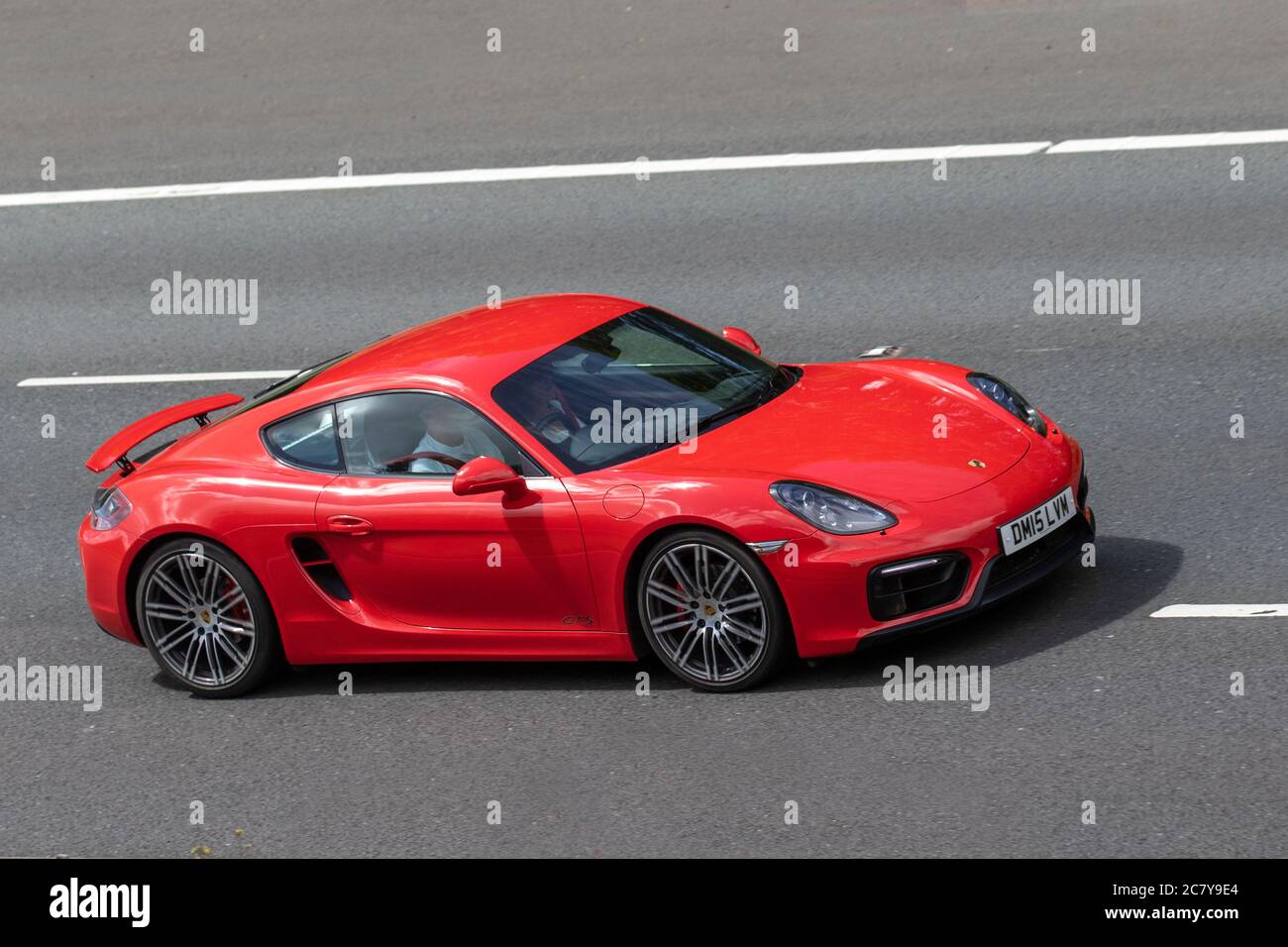 2015 red Porsche Cayman GTS S-A with spoiler up; Vehicular traffic moving vehicles, cars driving vehicles on UK roads, motors, motoring on the M6 motorway highway network. Stock Photo