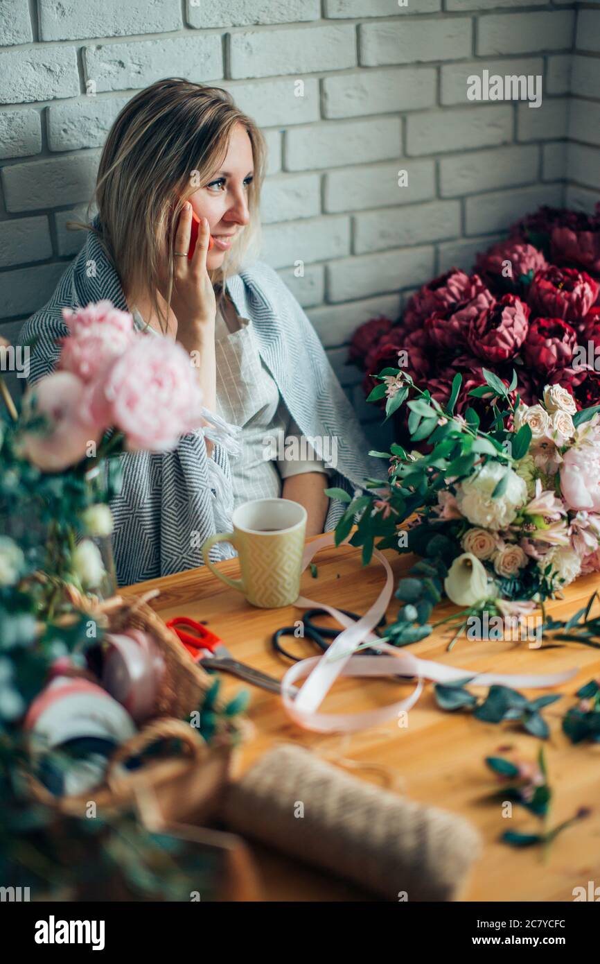 Smiling Mature Woman Florist Small Business Flower Shop Owner. She is using her telephone to take orders for her store Stock Photo