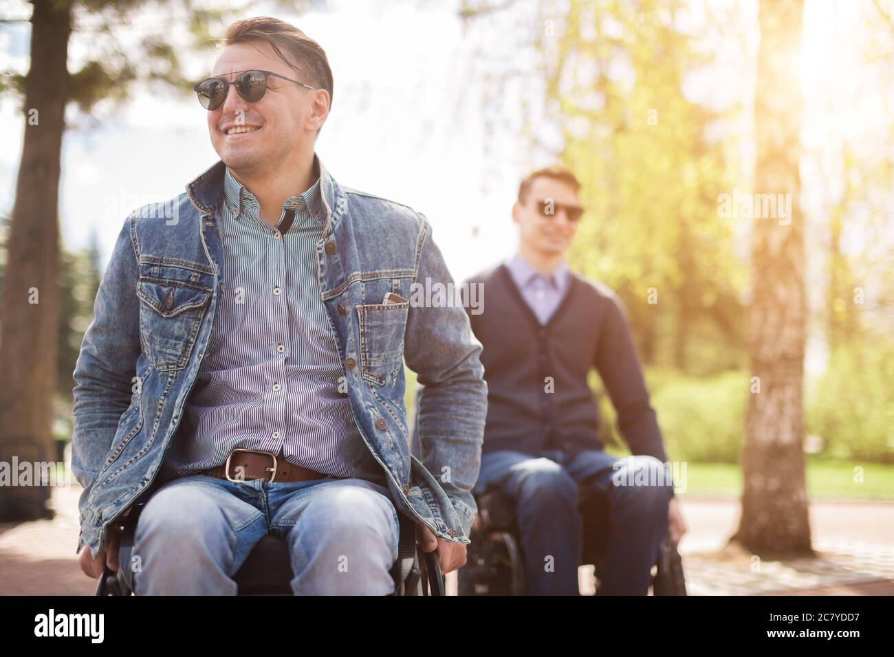 young man sitting on a wheelchair with his friend Stock Photo - Alamy