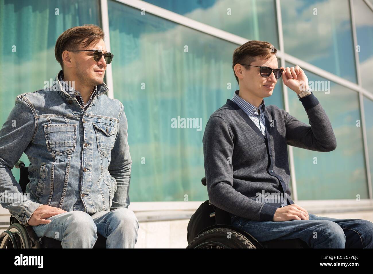 young man sitting on a wheelchair with his friend Stock Photo - Alamy