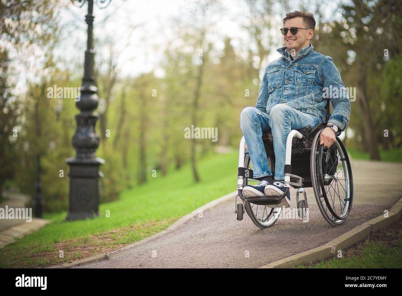 young disabled man in wheelchair walking park Stock Photo Alamy