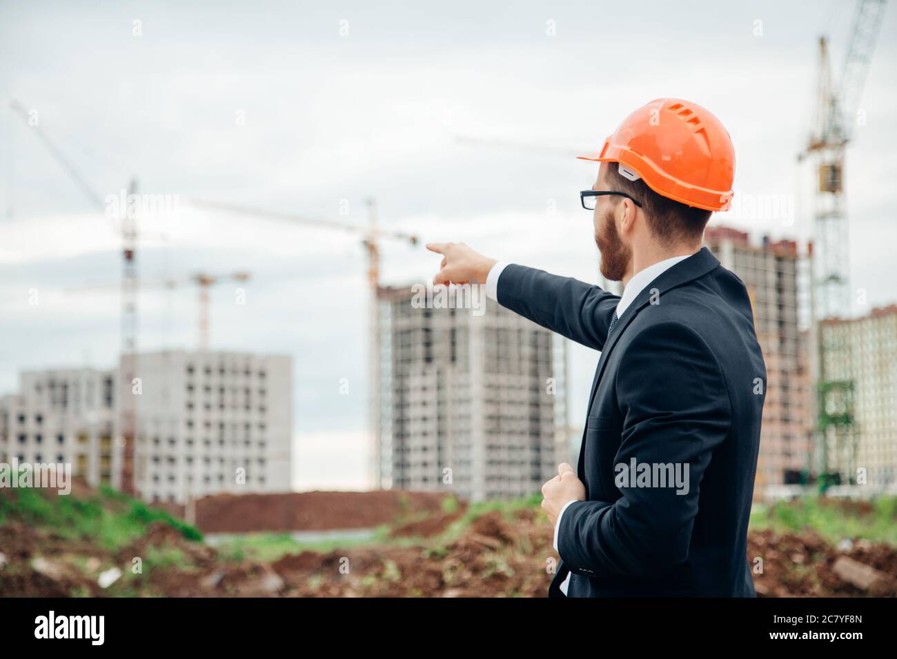 senior builder in hardhats pointing workers outdoors Stock Photo