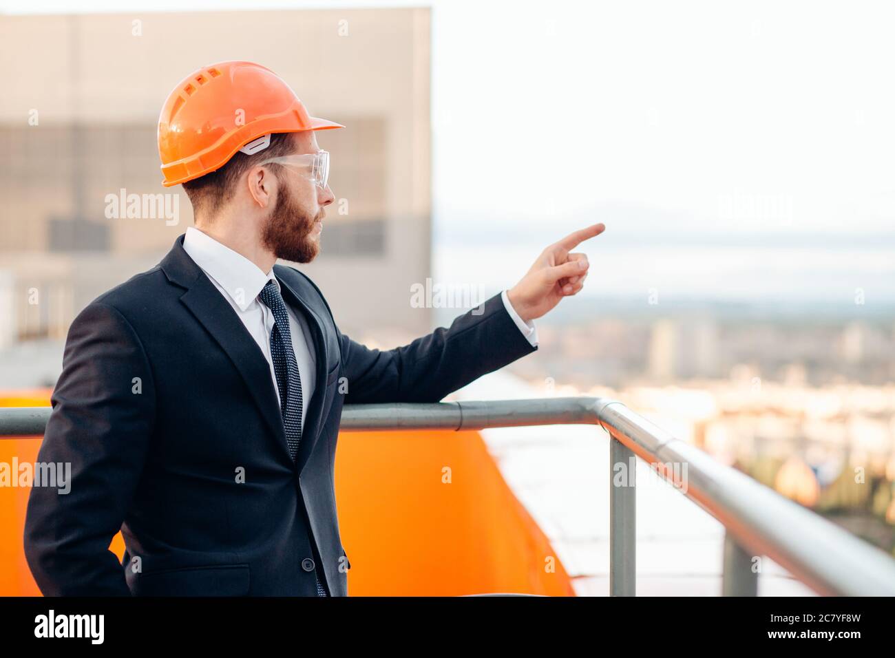 senior builder in hardhats pointing workers outdoors Stock Photo