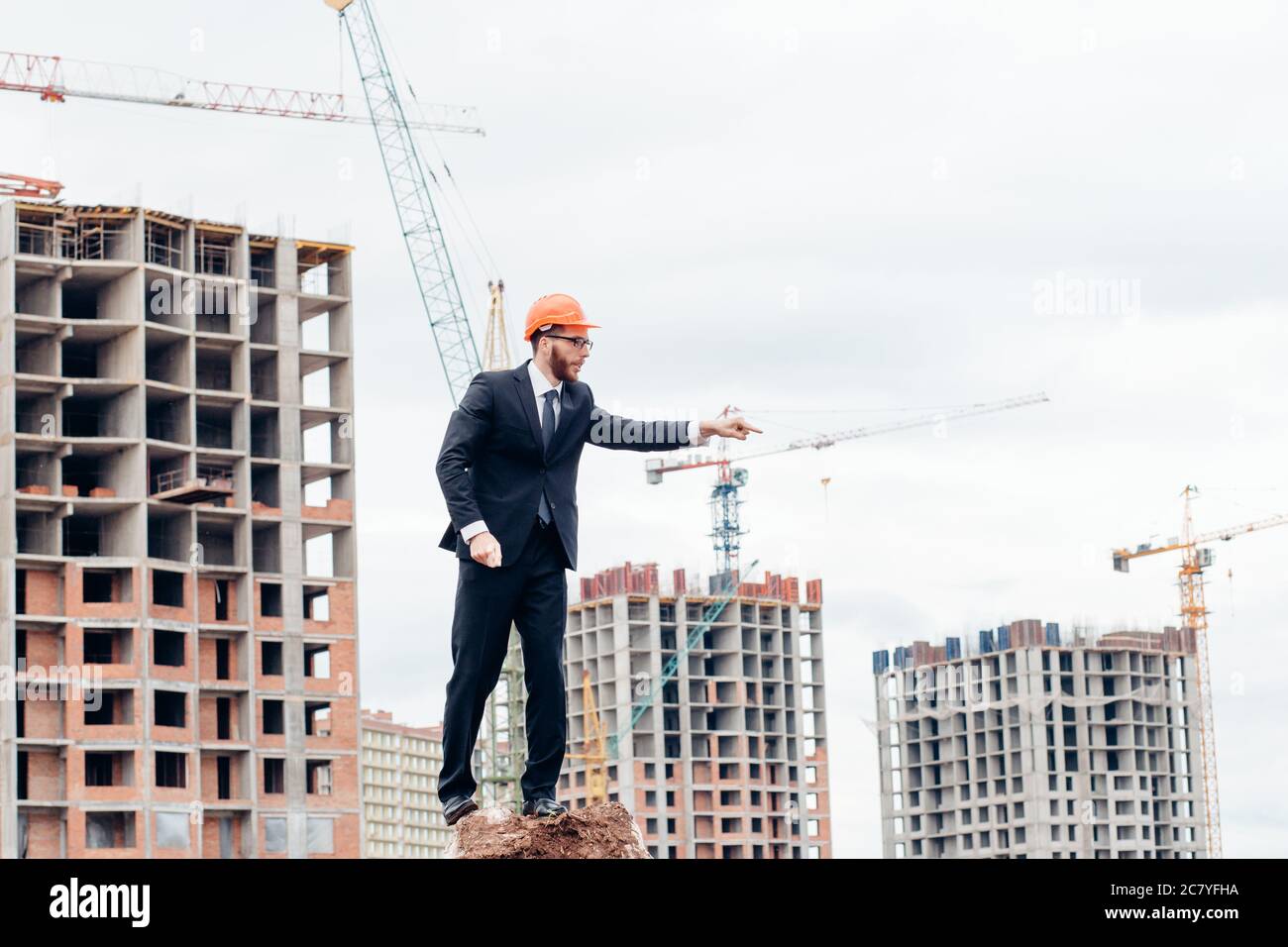 senior builder in hardhats pointing workers outdoors Stock Photo