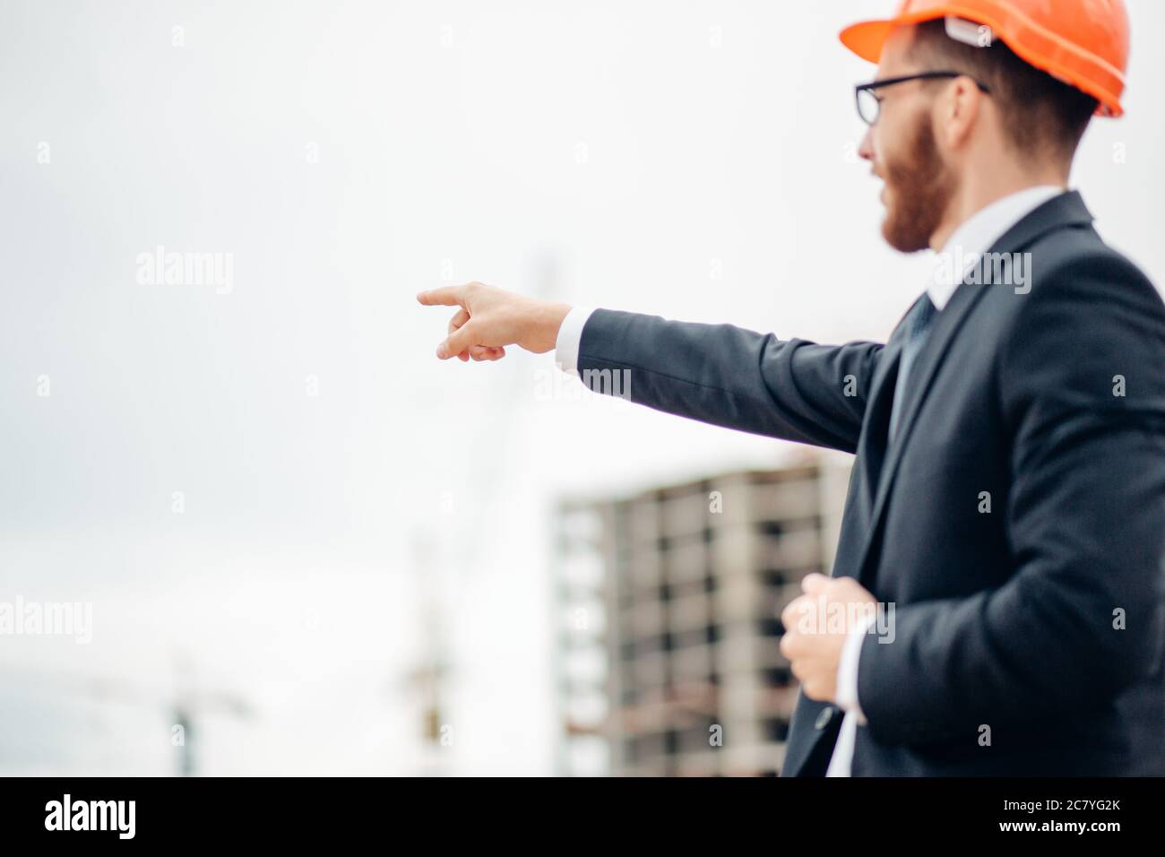 senior builder in hardhats pointing workers outdoors Stock Photo