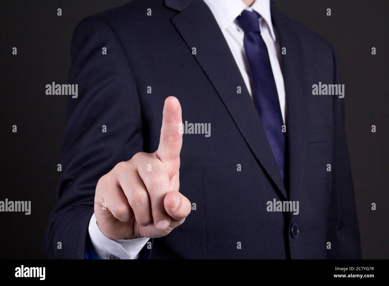businessman hand pressing an imaginary button on over dark background Stock Photo