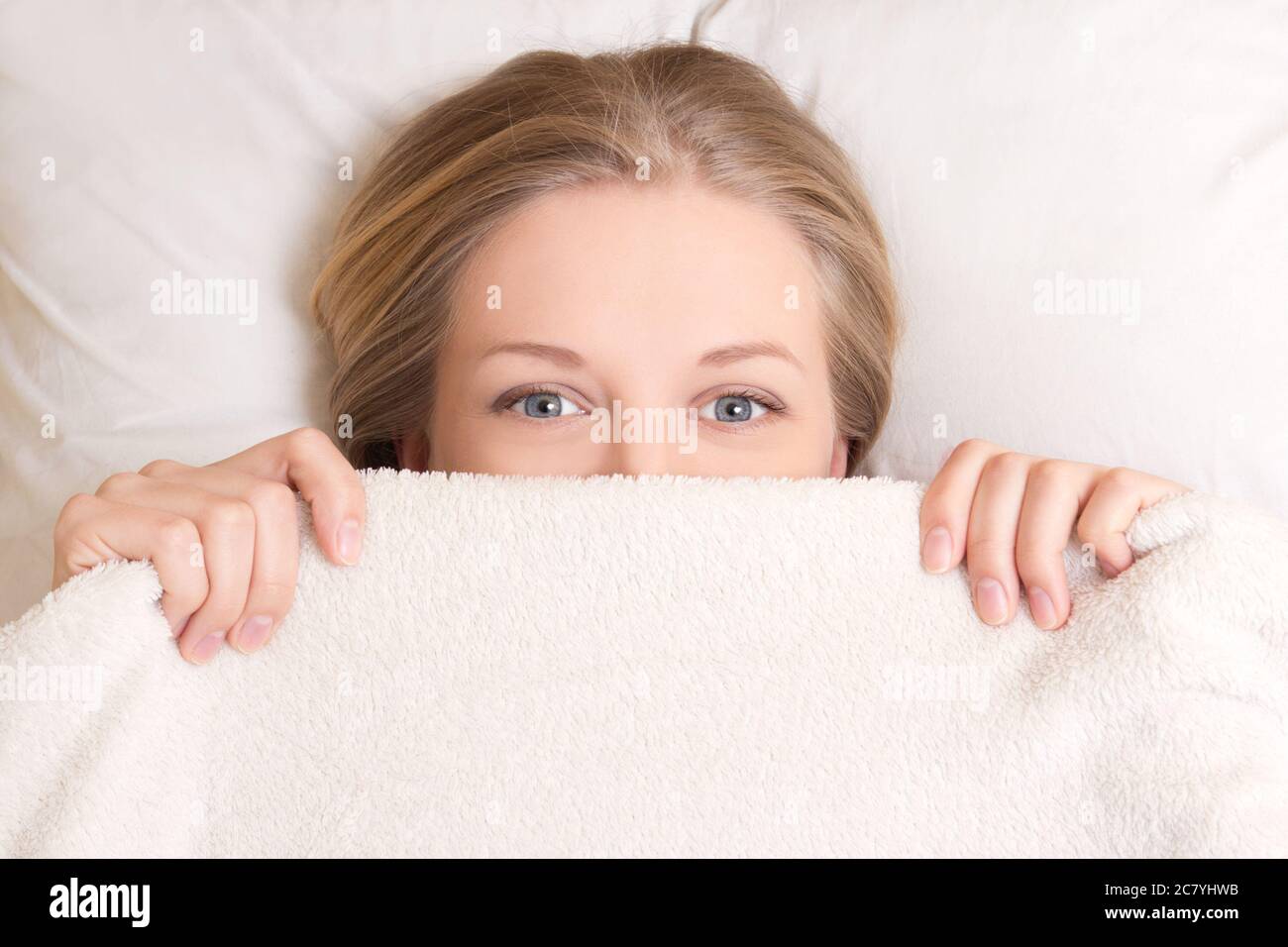 happy young beautiful woman lying in bed under blanket Stock Photo Alamy
