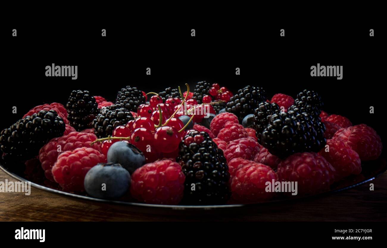 Fresh berries composition. Raspberries, blackberries, red currant and blueberries on black background. Tasty looking organic superfood Stock Photo