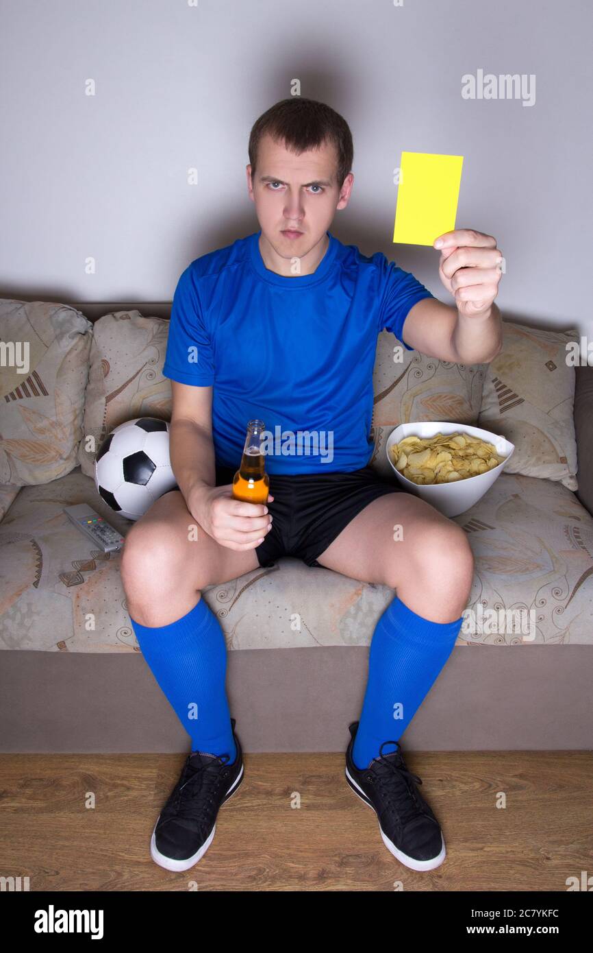 young attractive man watching football on tv at home and showing yellow card Stock Photo