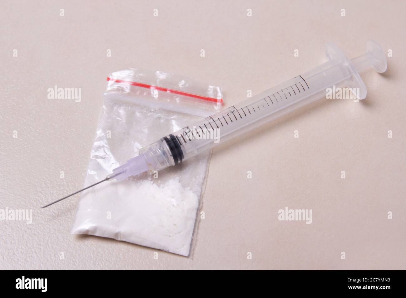 drug syringe and heroin powder in pack on tiled floor Stock Photo
